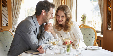 Lachendes Paar hält Händchen und sitzt an einem Tisch in einem Restaurant 